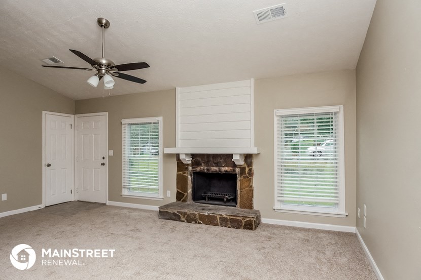 a living room with a fireplace and a ceiling fan
