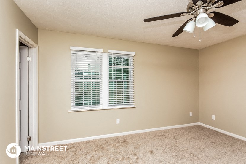 the master bedroom has a ceiling fan and a large window