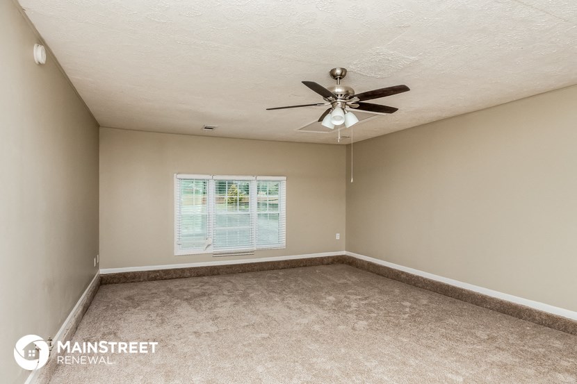 an empty room with a ceiling fan and a window