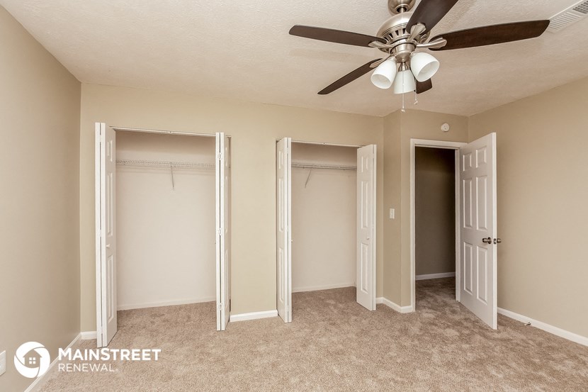 a bedroom with three closets and a ceiling fan