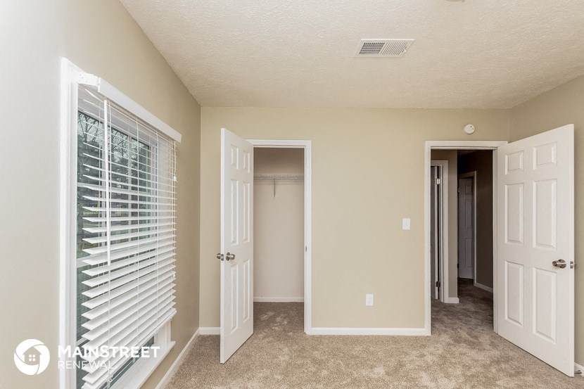 a bedroom with a closet and a window and a door to a closet