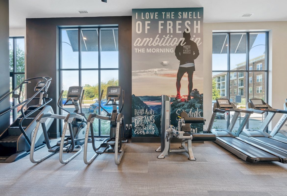 a gym with cardio machines and a large wall mural of a man on a skate