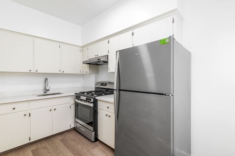 A kitchen with a stainless steel refrigerator, oven, and sink.