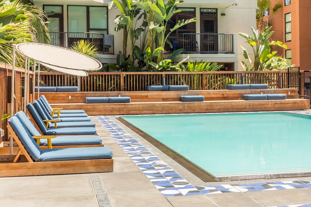 a swimming pool with blue lounge chairs and a poolside umbrella