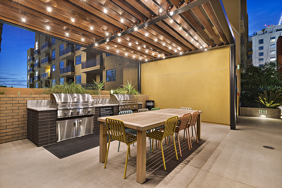 a outdoor kitchen with a dining table and barbecue grill