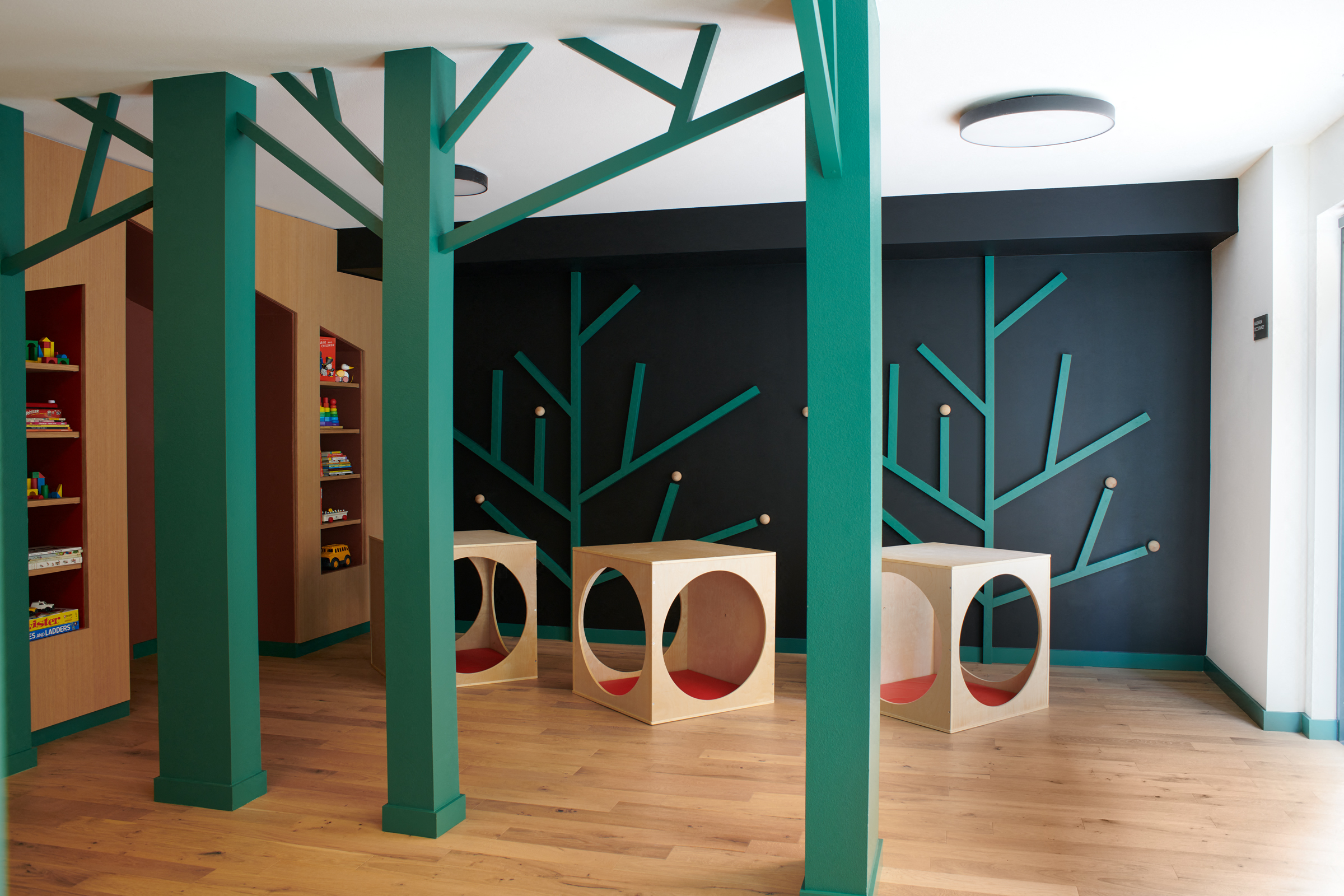 a room with green columns and a tree mural on the wall