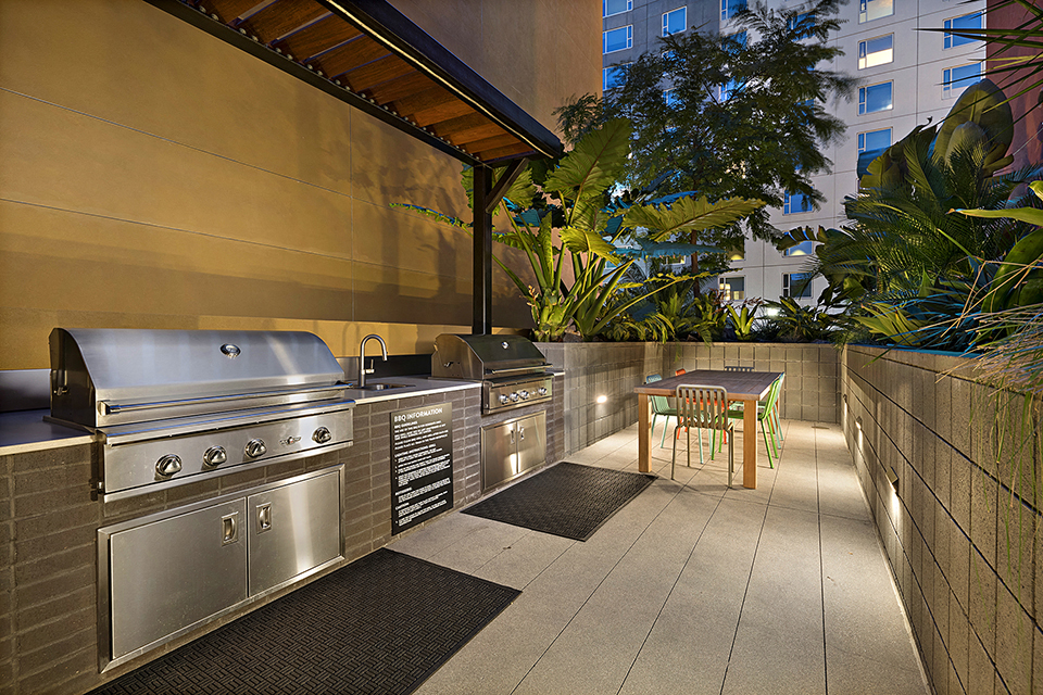 the outdoor kitchen has stainless steel appliances and a grill and a table
