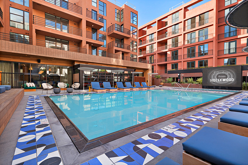 a swimming pool with blue chairs in front of an apartment building