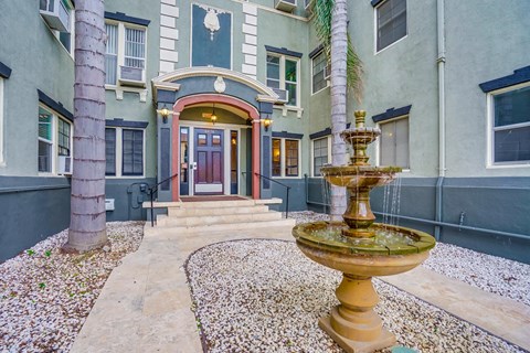 a fountain in front of a house with a front door