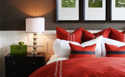 a bed with red and white pillows and a lamp