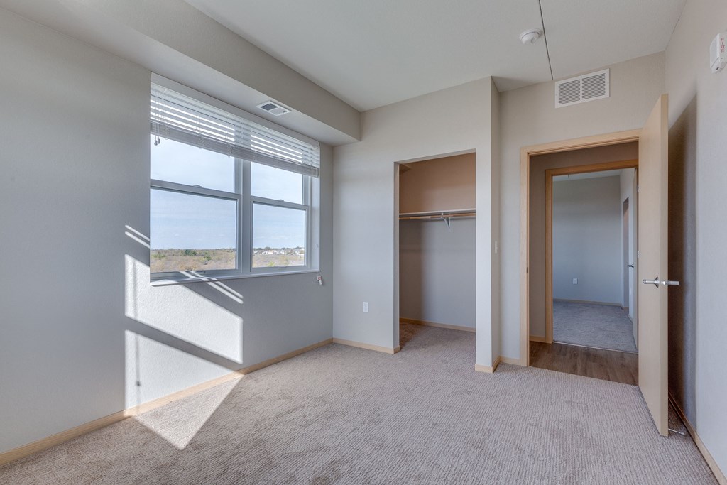 an empty bedroom with a window and a closet