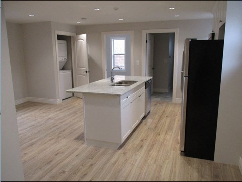 A kitchen with a white counter top and a black refrigerator.