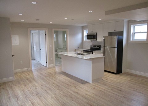 A kitchen with a white island and black refrigerator.