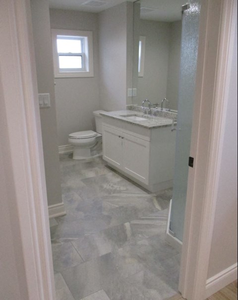 A bathroom with a toilet, sink, and a window.
