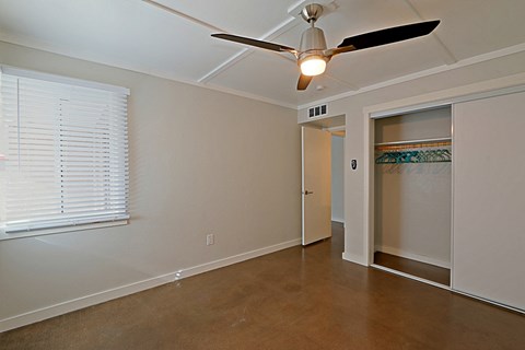 an empty living room with a ceiling fan and a closet