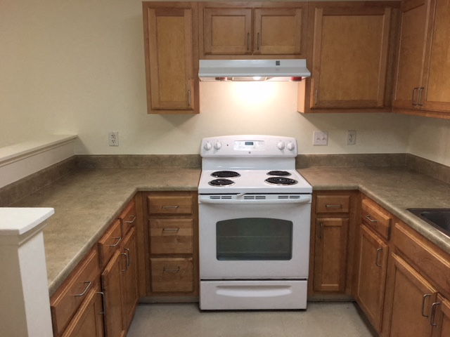 an empty kitchen with a stove and cabinets