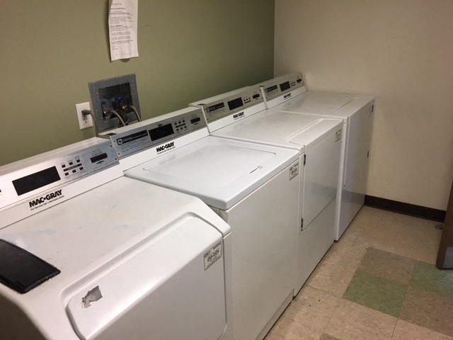 four washing machines lined up in a row in a laundry room