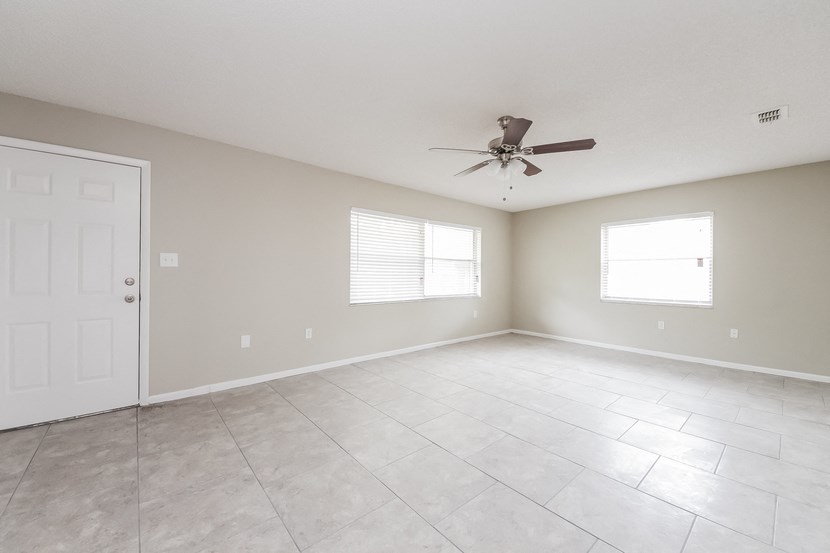 the spacious living room with ceiling fan and tiled floor