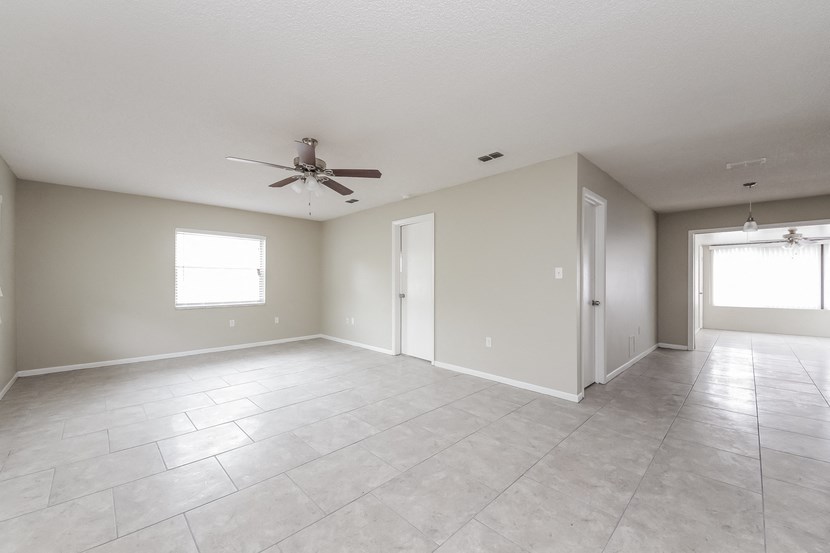 an empty living room with a ceiling fan