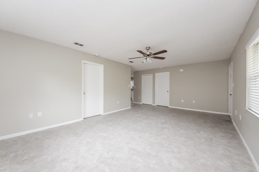 an empty living room with a ceiling fan