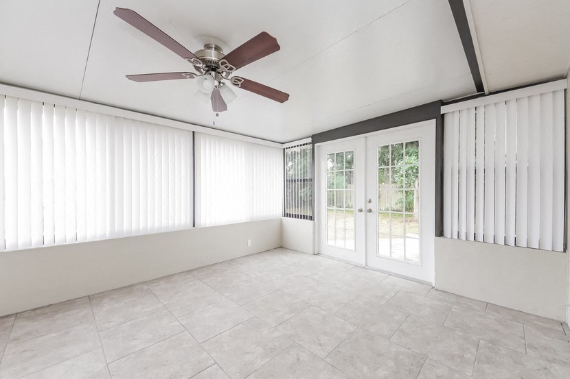 an empty living room with a ceiling fan and sliding glass doors