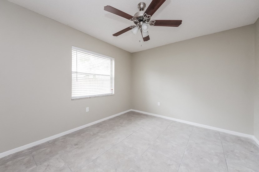 an empty room with a ceiling fan and a window