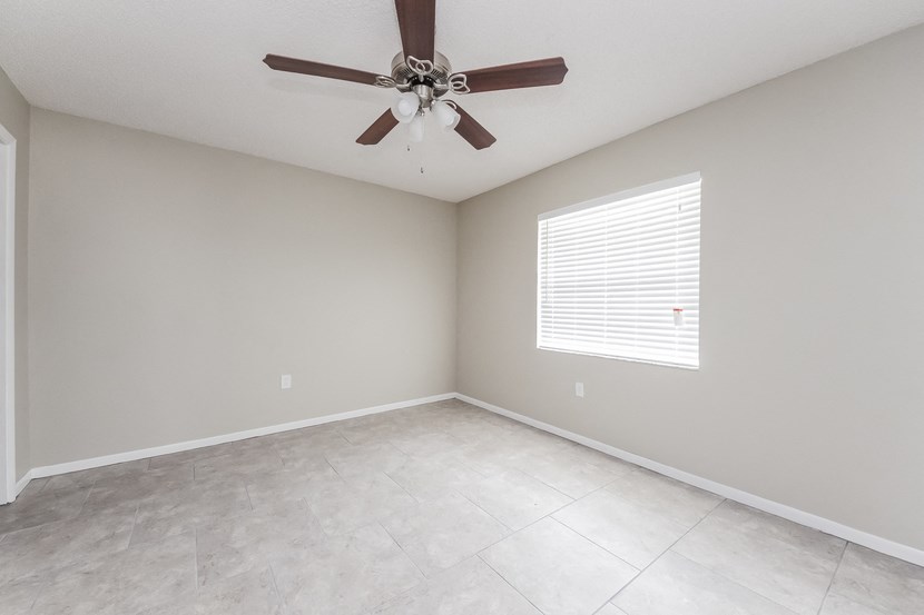 an empty living room with a ceiling fan and a tiled floor