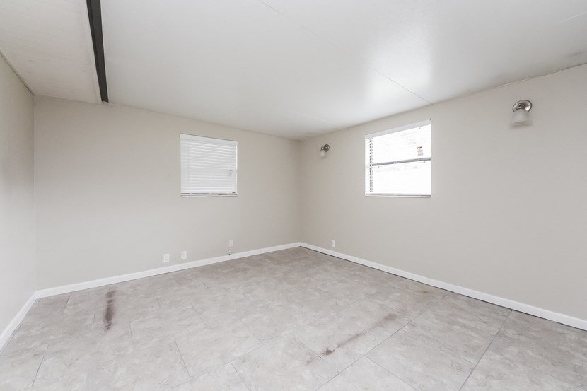 the living room of an empty home with white walls and a window