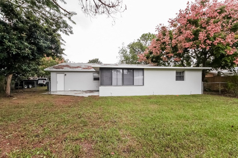 a small white house with a yard and trees