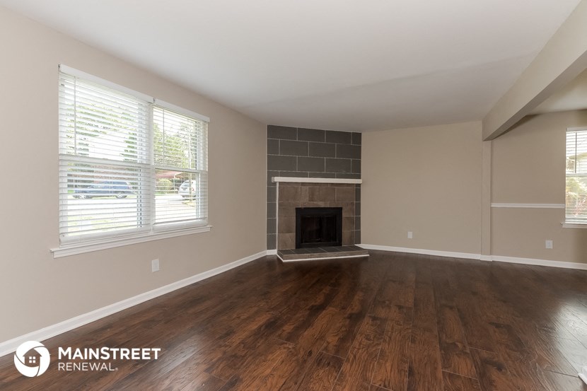 the living room of a home with wood flooring and a fireplace