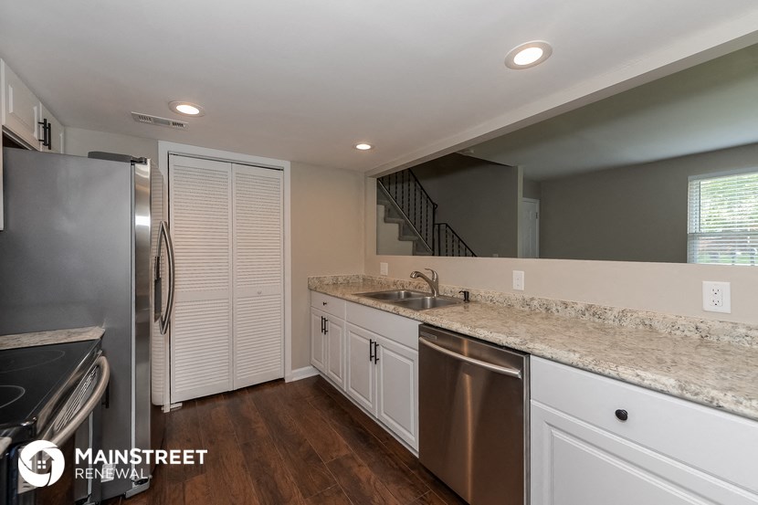 a kitchen with white cabinets and granite counter tops and a stainless steel refrigerator