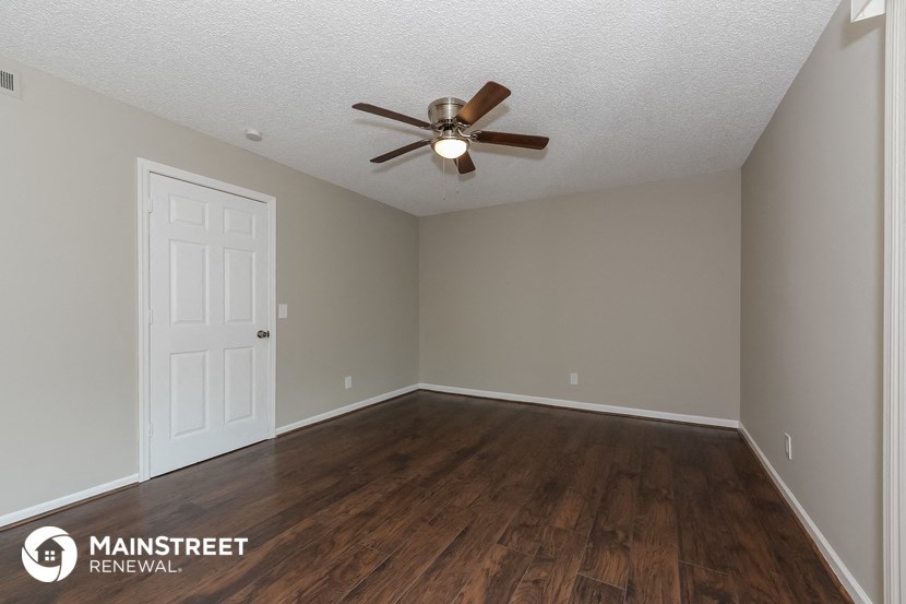 the spacious living room of this manufactured home has a ceiling fan and wood flooring