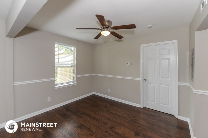 the interior of a bedroom with wood flooring and a ceiling fan