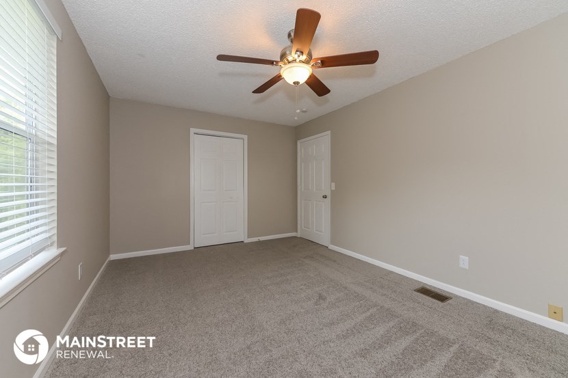 the spacious living room with ceiling fan and window