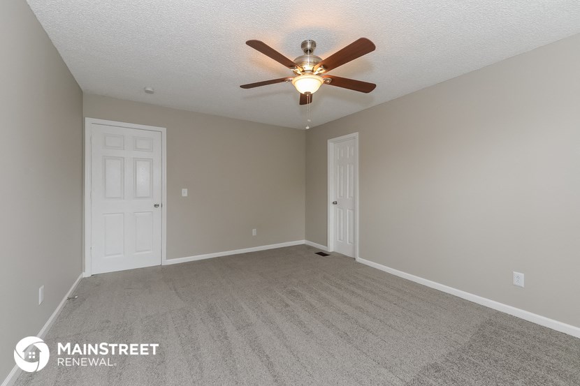 the spacious living room with ceiling fan and carpet