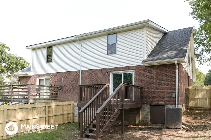 the back of a brick house with a wooden deck and stairs