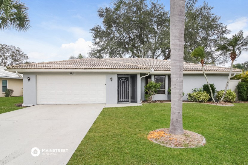 a white house with a driveway and a palm tree