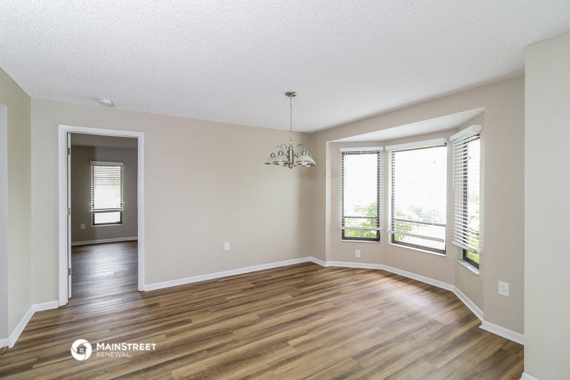 an empty living room with wood flooring and windows