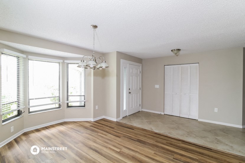 the living room and dining room of an empty house with wood flooring and windows