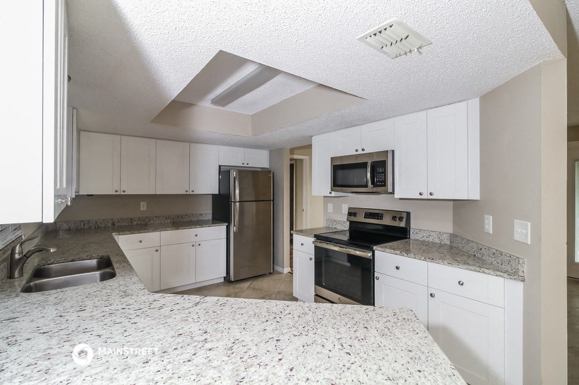 a large kitchen with white cabinets and stainless steel appliances