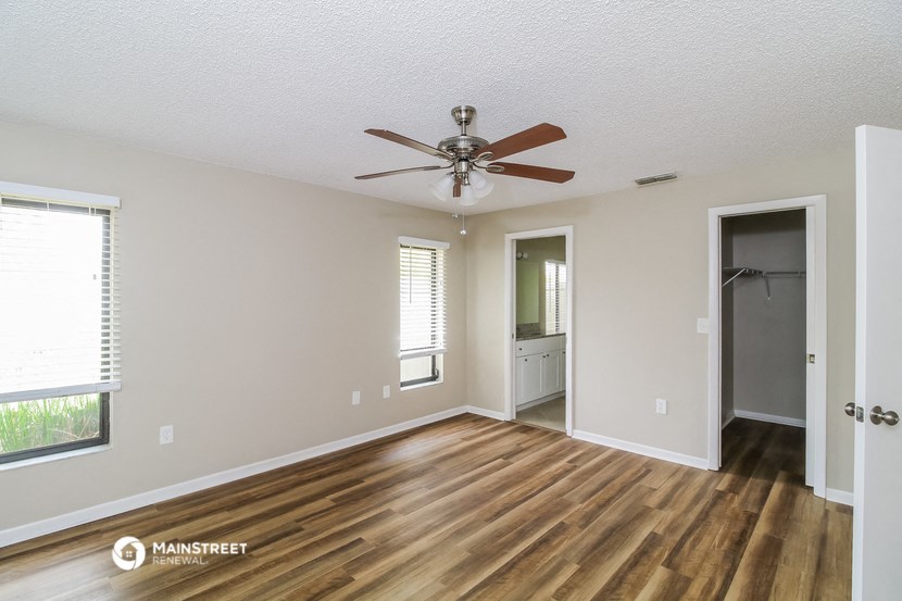 an empty living room with a ceiling fan and a closet