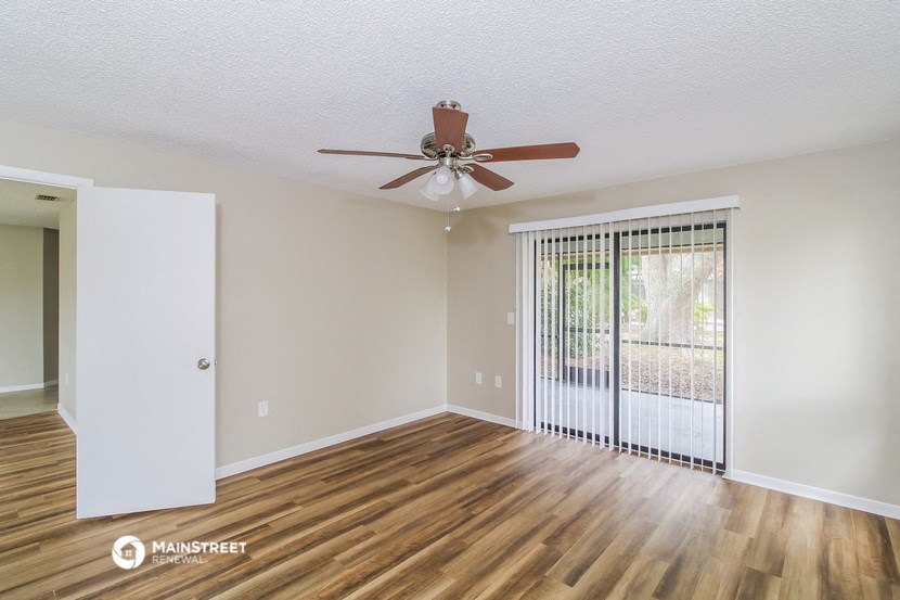 an empty living room with a ceiling fan and a window