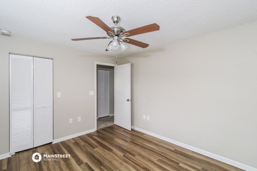 a living room with a ceiling fan and a closet