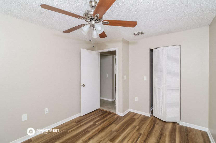 a living room with a ceiling fan and a closet