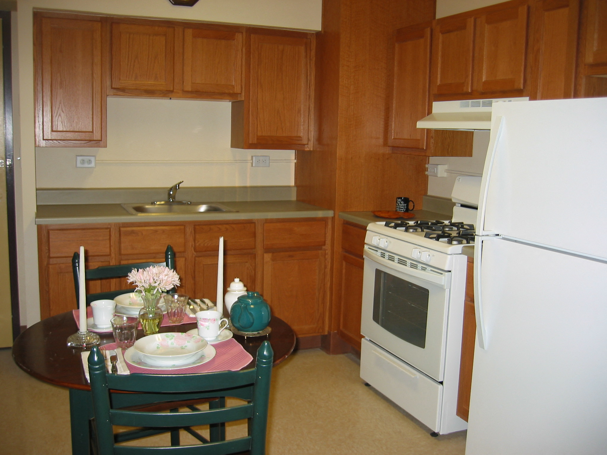 a kitchen with white appliances and a table and chairs