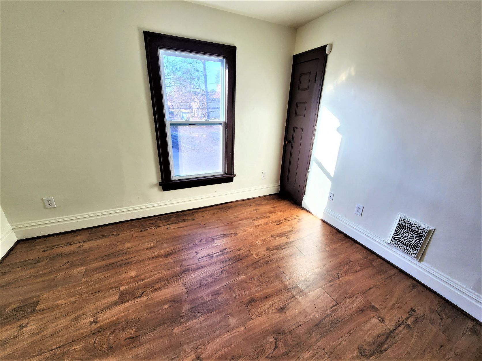 a empty living room with wood floors and a window