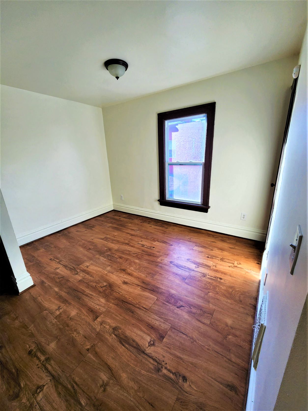a empty room with a window and wooden floors