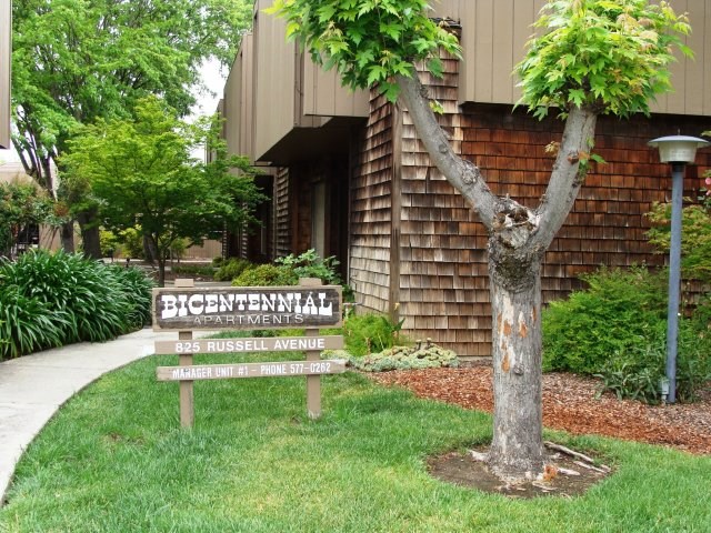 a sign in the grass in front of a building