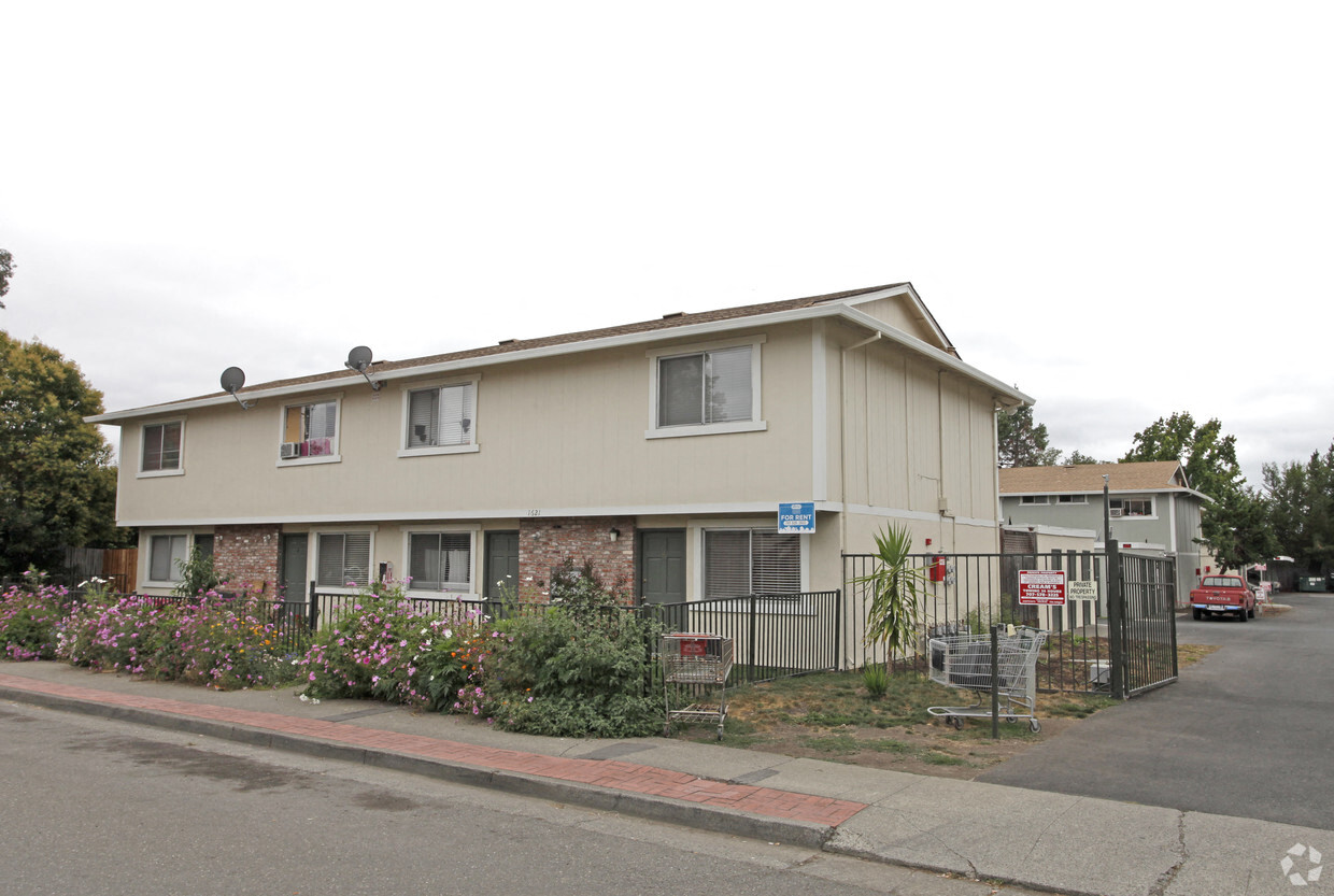 A beige house with a blue sign in front of it.