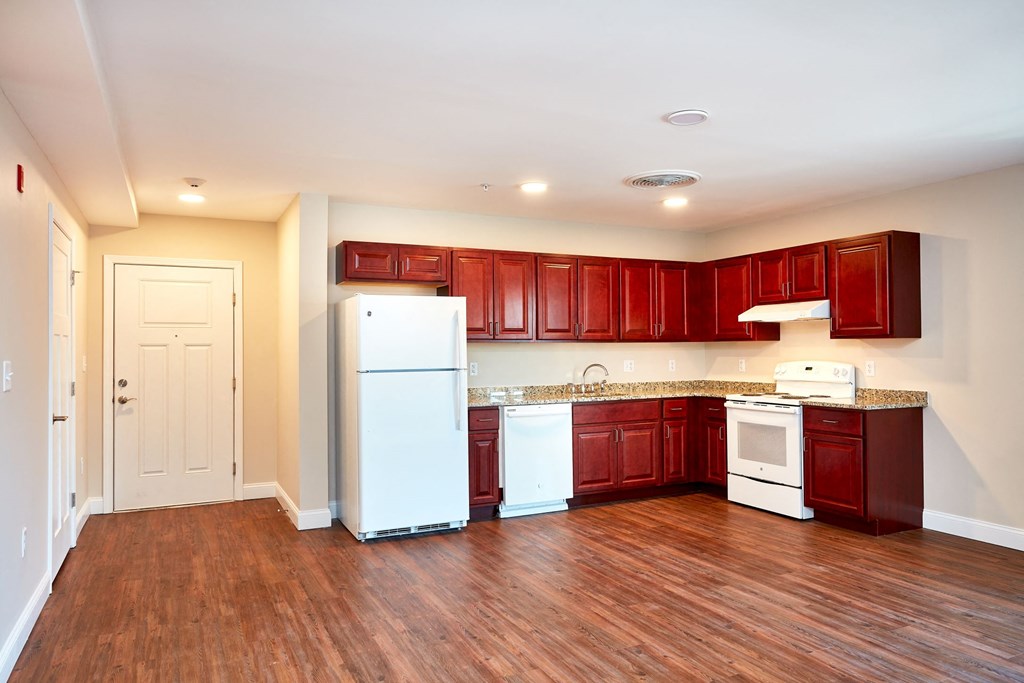 a large kitchen with white appliances and wooden floors